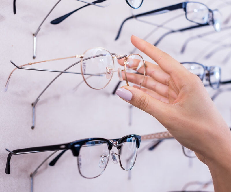 A hand reaches for a pair of eyeglasses from a display of various frames - Eyeglass frames