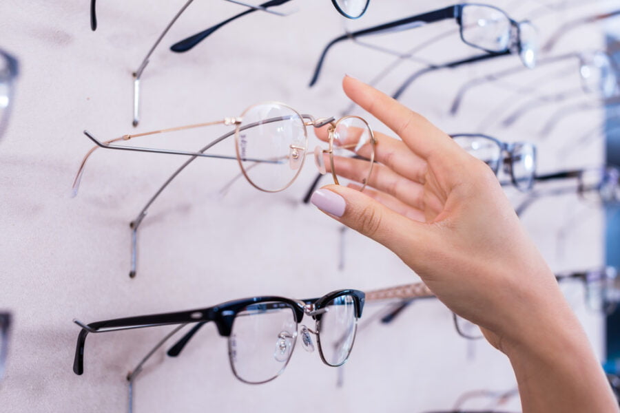 A hand reaches for a pair of eyeglasses from a display of various frames - Eyeglass frames